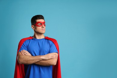 Photo of Man wearing superhero cape and mask on light blue background. Space for text
