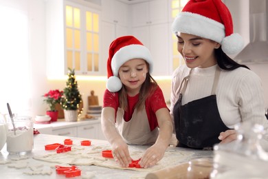 Mother with her cute little daughter making Christmas cookies in kitchen