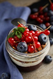 Photo of Delicious yogurt parfait with fresh berries and mint on wooden table, closeup