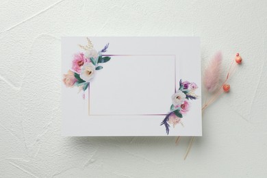 Photo of Blank invitation card and dry flowers on white table, flat lay