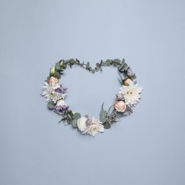 Beautiful heart made of different flowers on light gray background, flat lay. Space for text