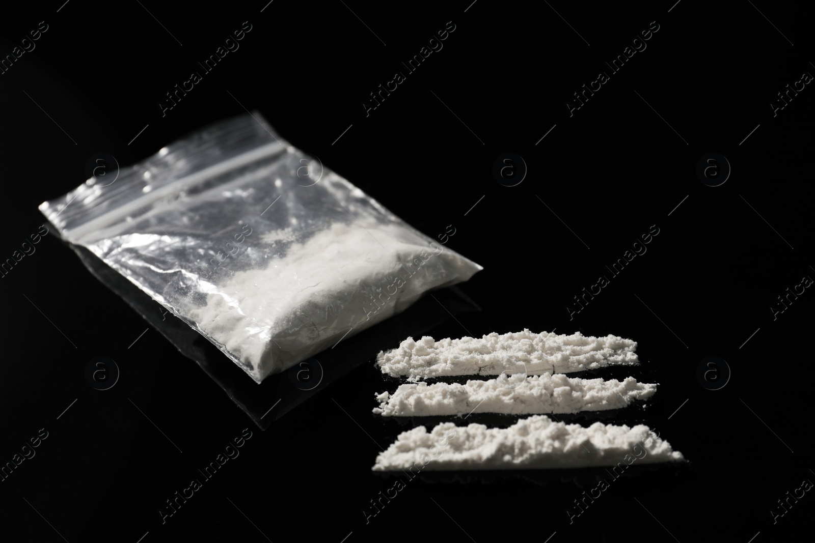 Photo of Drug addiction. Plastic bag with cocaine on black table