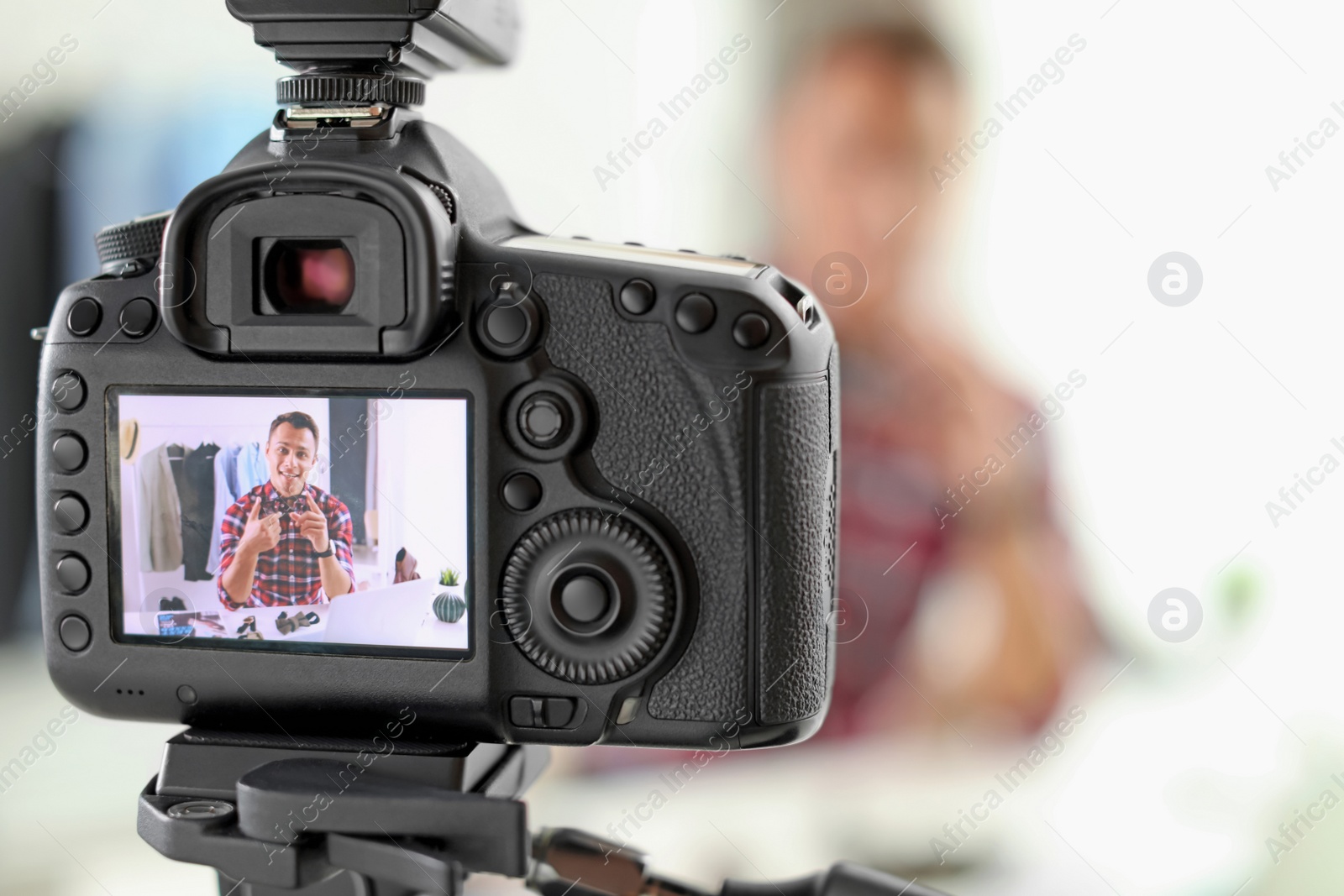 Photo of Fashion blogger recording video indoors, focus on camera display. Space for text