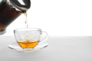 Photo of Pouring hot tea into glass cup on white background