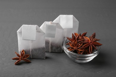 Photo of Tea bags with anise stars on grey table, closeup