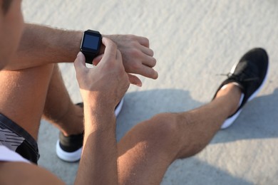 Photo of Man checking fitness tracker after training outdoors, closeup