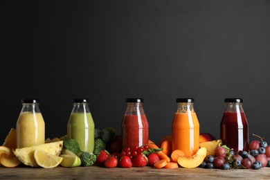 Photo of Bottles of delicious juices and fresh fruits on wooden table