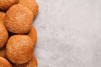 Photo of Fresh buns with sesame seeds on light grey table, flat lay. Space for text