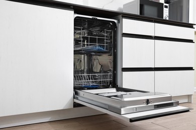 Open clean empty dishwasher in kitchen. Home appliance