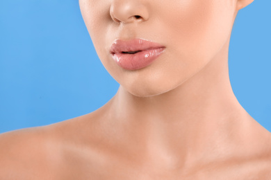 Photo of Young woman with beautiful full lips on light blue background, closeup