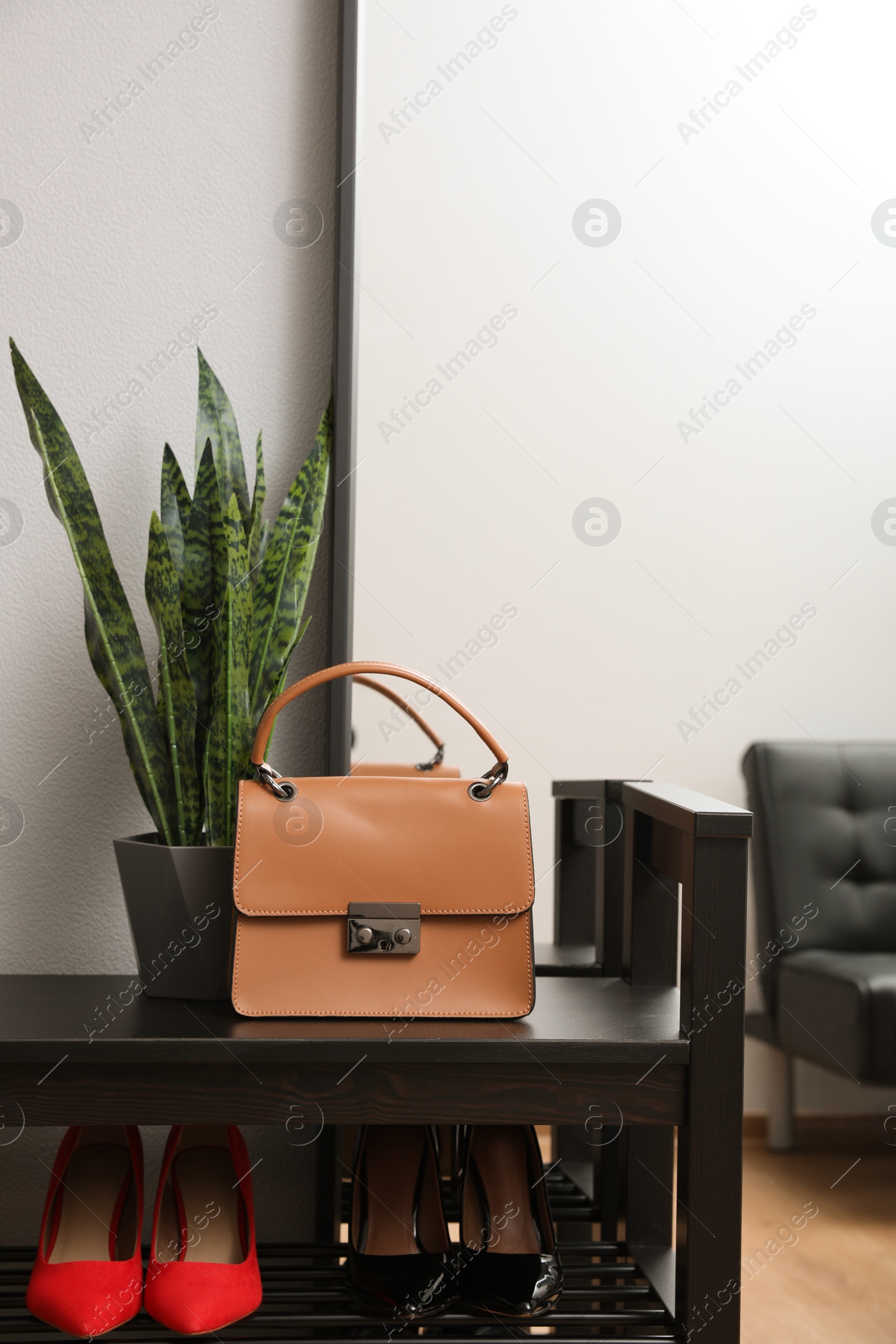 Photo of Shelving unit with stylish shoes and bag near grey wall in hallway