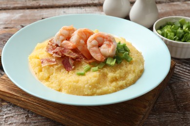 Photo of Plate with fresh tasty shrimps, bacon, grits and green onion on wooden table, closeup