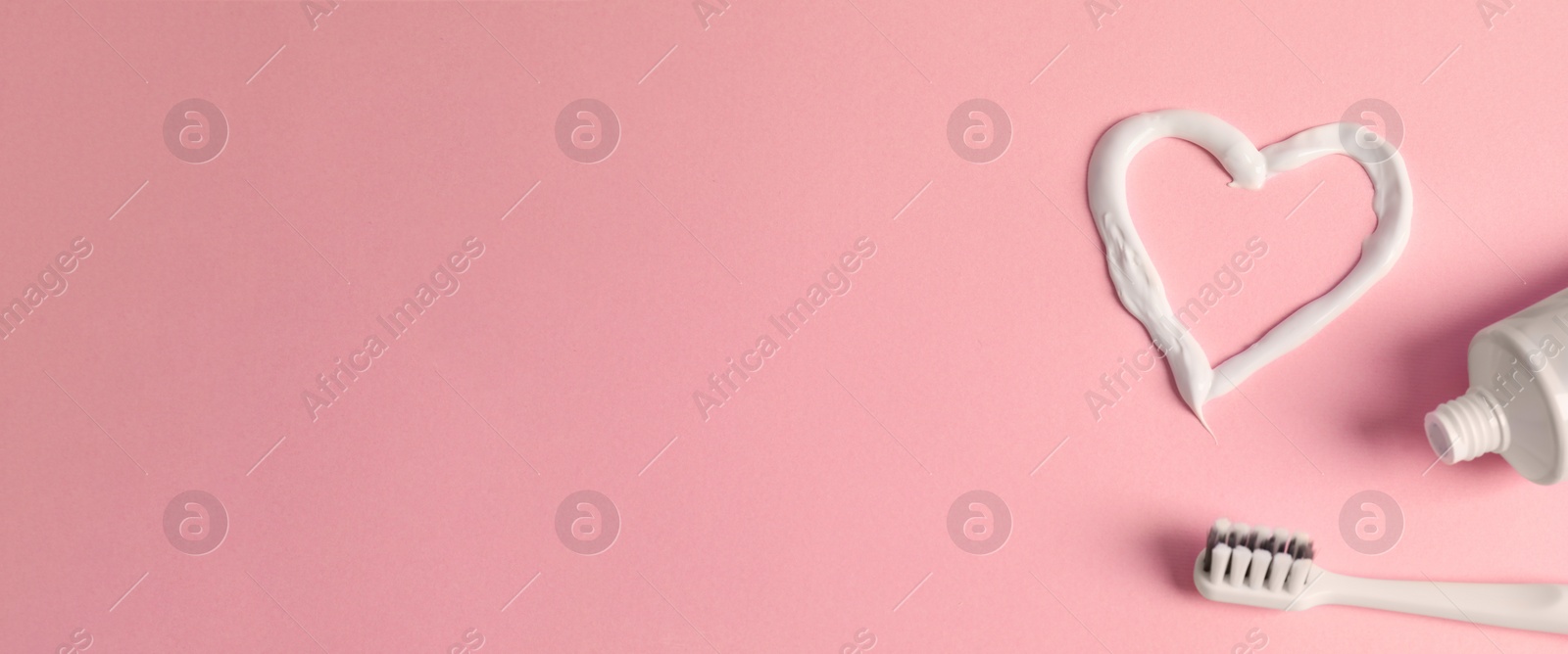 Image of Heart shape made of toothpaste, brush and tube on light pink background, flat lay with space for text. Banner design