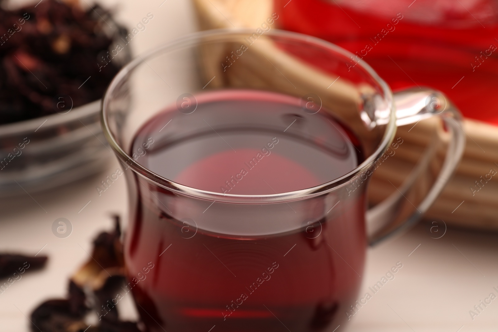 Photo of Cup of delicious hibiscus tea on white table, closeup