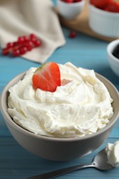 Photo of Tasty cream cheese and fresh berries on light blue wooden table