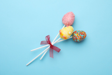 Egg shaped cake pops for Easter celebration on light blue background, top view