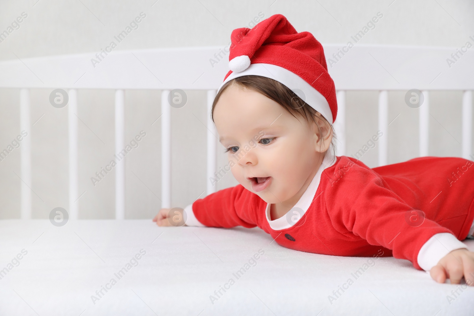 Photo of Cute baby wearing festive Christmas costume in crib. Space for text