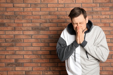 Photo of Man suffering from cold near brick wall. Space for text