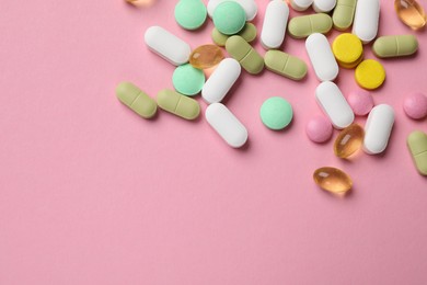 Photo of Different vitamin pills on pink background, top view. Space for text