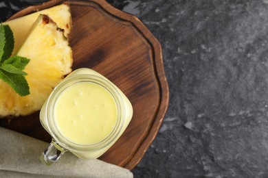 Photo of Tasty pineapple smoothie on dark textured table, flat lay. Space for text