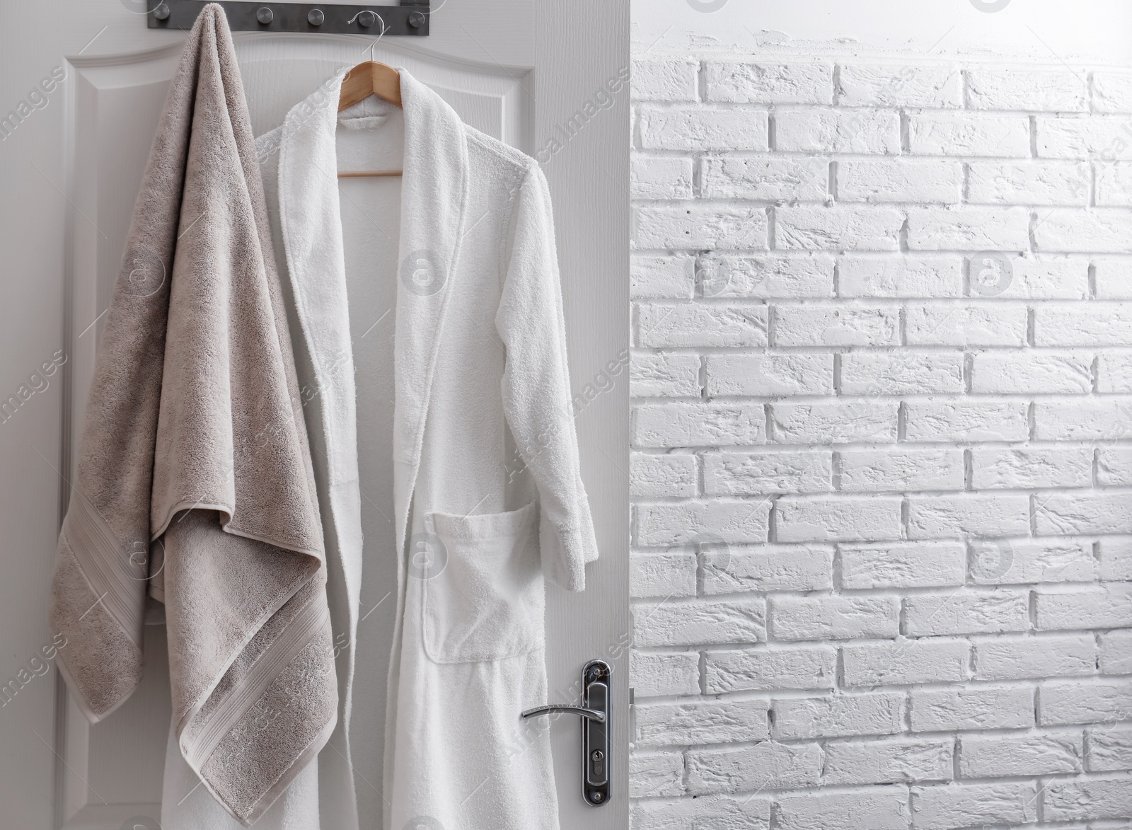 Photo of Hanger with clean towel and bathrobe on door