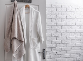 Hanger with clean towel and bathrobe on door