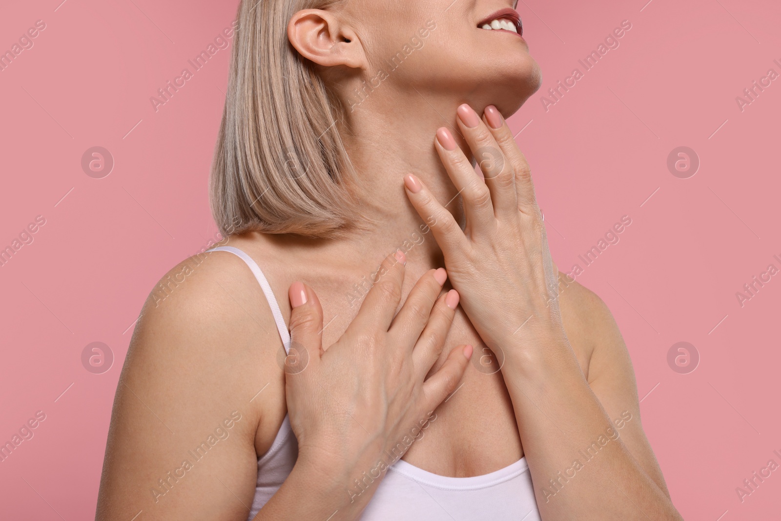 Photo of Woman touching her neck on pink background, closeup