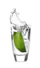 Lime slice falling into shot glass of vodka on white background