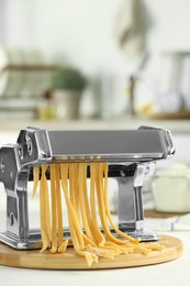 Photo of Pasta maker with raw dough on white table