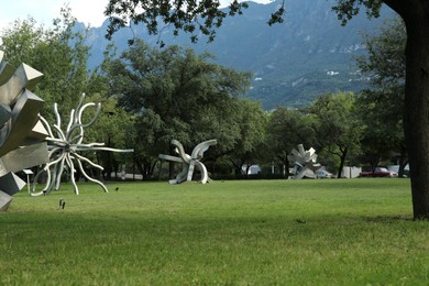 Photo of Picturesque view of beautiful park with metal figures on green grass