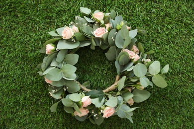 Photo of Wreath made of beautiful flowers on green grass outdoors, top view