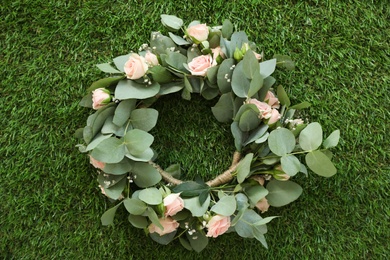 Wreath made of beautiful flowers on green grass outdoors, top view