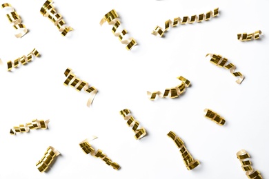 Photo of Shiny golden serpentine streamers on white background, top view