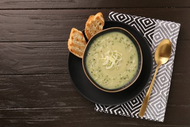 Photo of Delicious leek soup served on brown wooden table, top view. Space for text