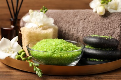 Aromatic sea salt and spa products on wooden table, closeup