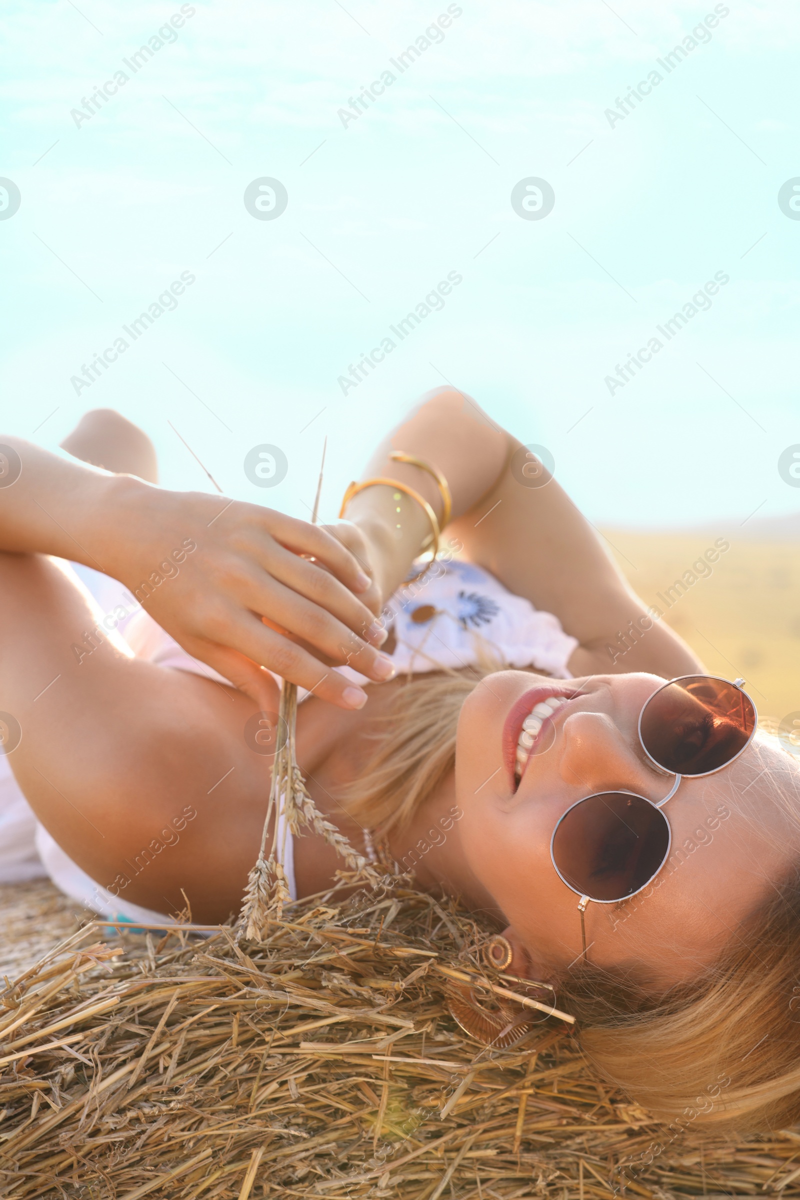 Photo of Beautiful hippie woman with spikelets on hay bale in field