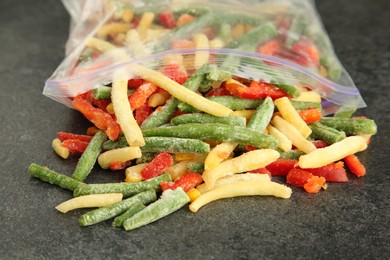 Photo of Zip bag with different frozen vegetables on grey table, closeup