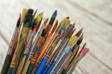 Photo of Different paint brushes on light blurred background, closeup