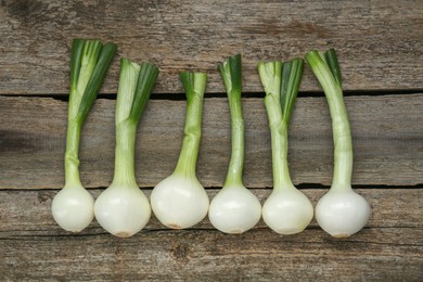 Photo of Whole green spring onions on wooden table, flat lay