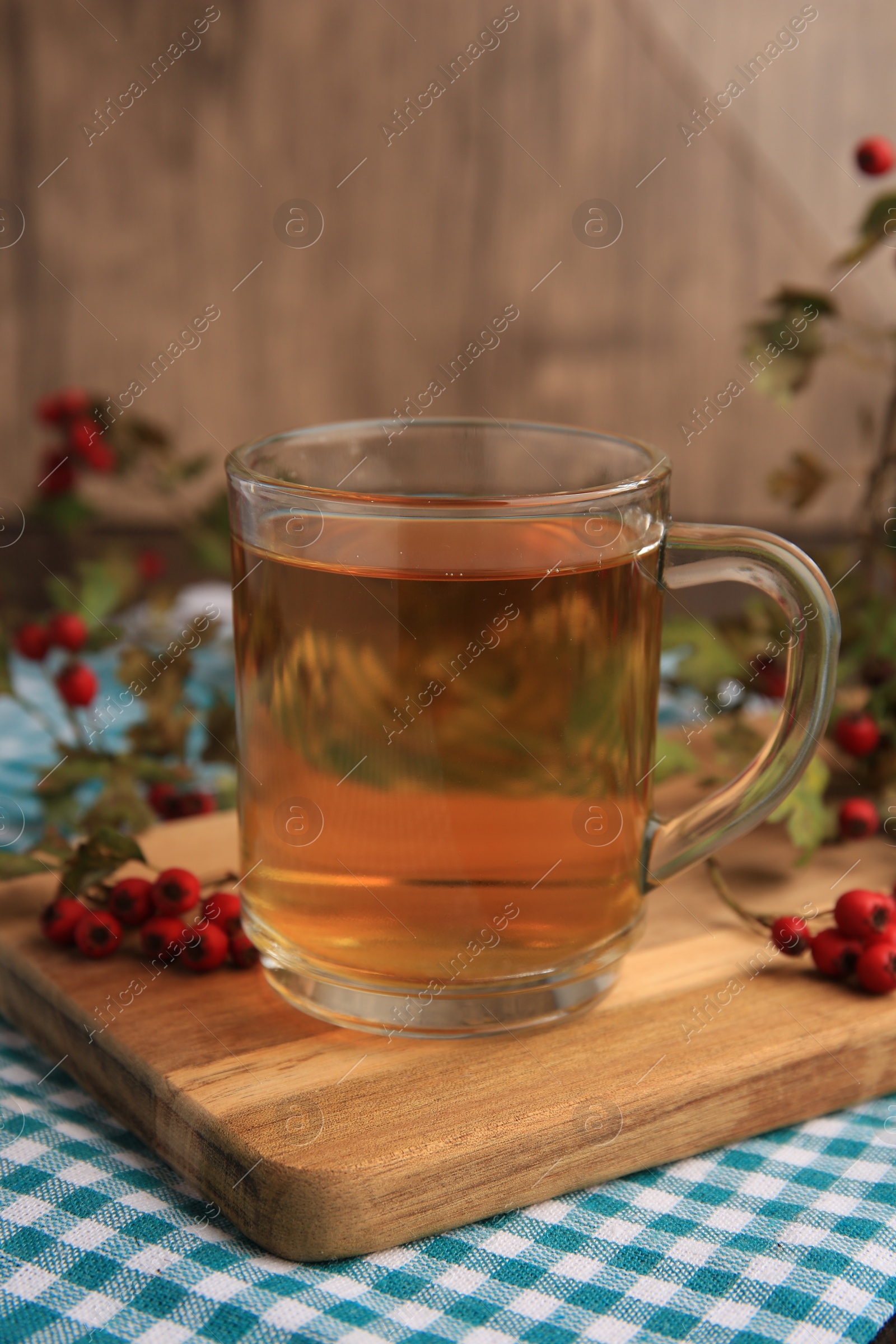 Photo of Cup with hawthorn tea and berries on table, closeup