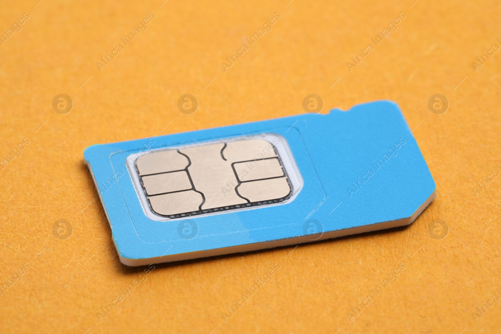 Photo of Mini SIM card on orange background, closeup