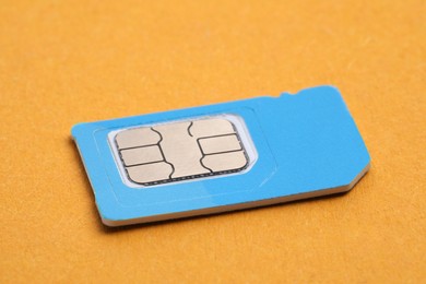 Photo of Mini SIM card on orange background, closeup