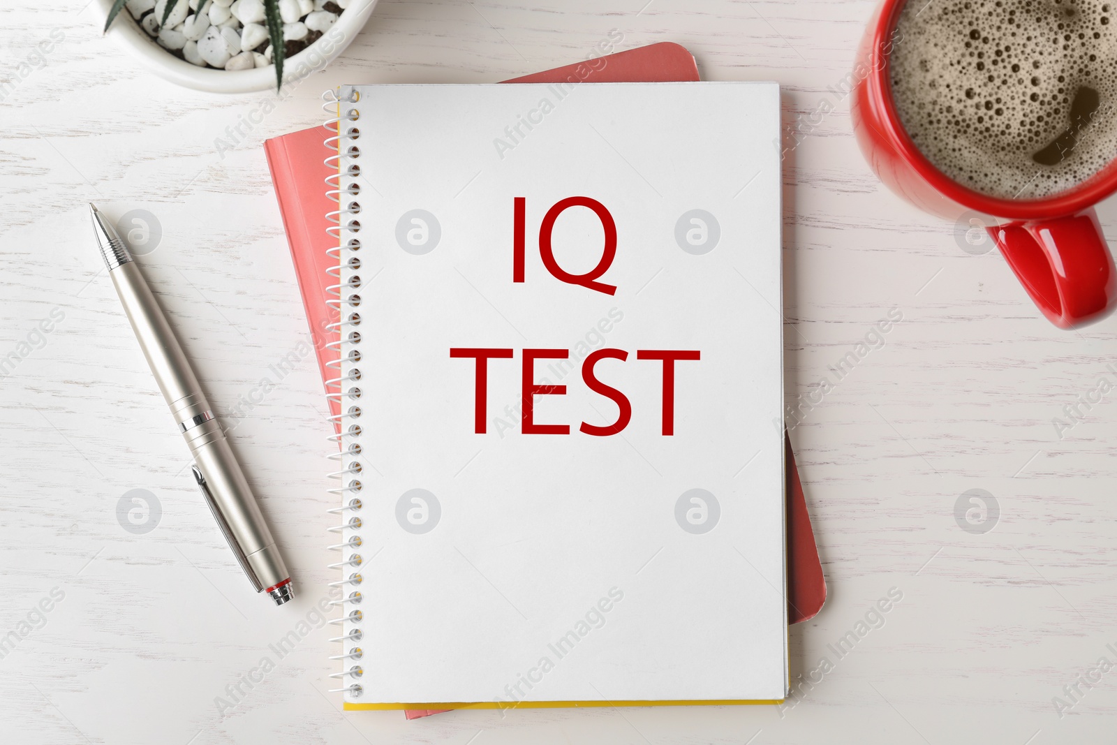 Image of Notebook with text IQ Test, pen and cup of coffee on white wooden table, flat lay