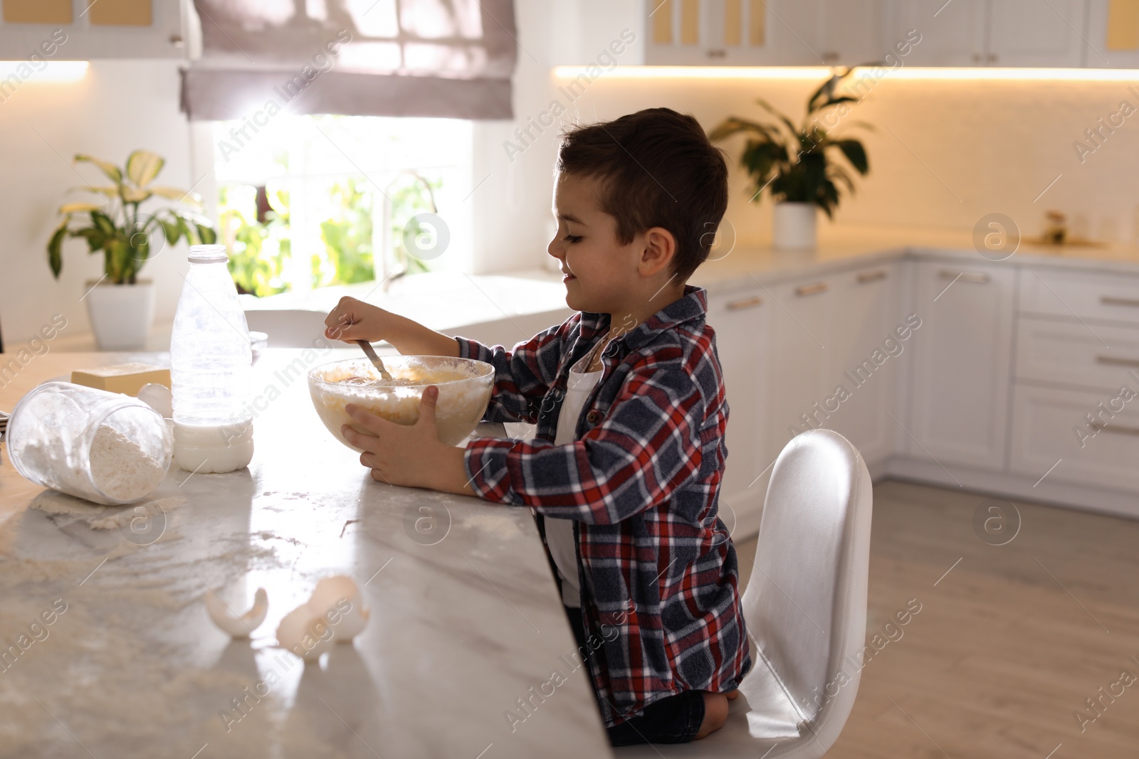 Photo of Cute little boy cooking dough in kitchen at home