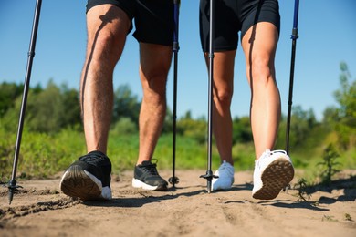 Photo of Couple practicing Nordic walking with poles outdoors on sunny day, closeup