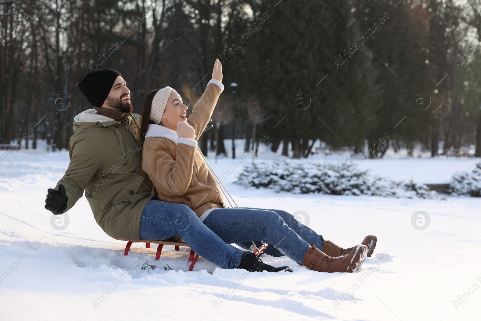 Photo of Happy young couple sledding outdoors on winter day