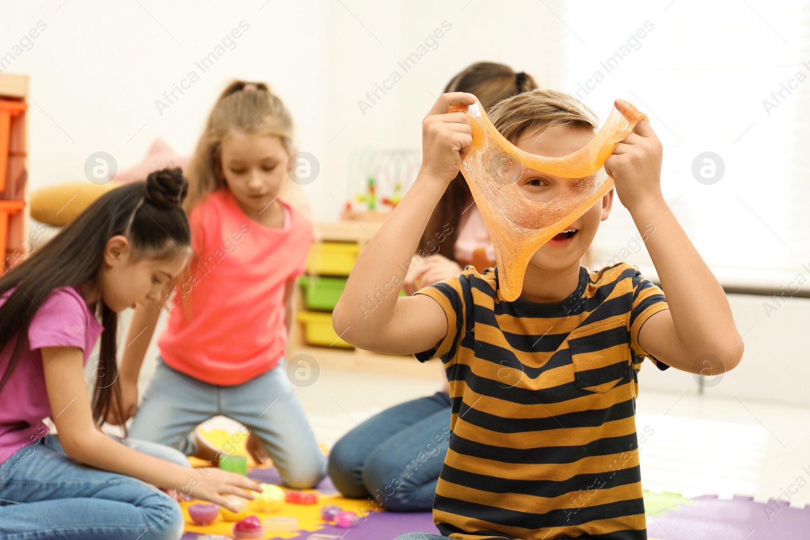 Photo of Preteen boy playing with slime in room
