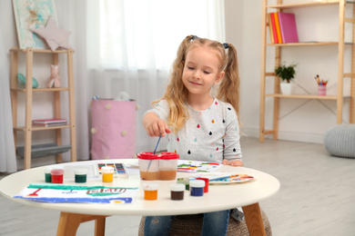Photo of Cute little child painting at table in room