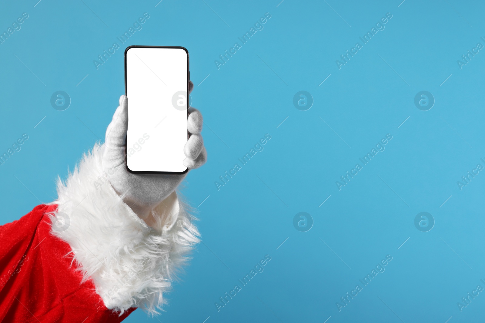 Photo of Merry Christmas. Santa Claus showing smartphone on light blue background, closeup. Mockup for design