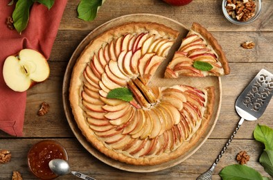 Photo of Delicious apple pie and ingredients on wooden table, flat lay